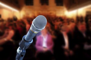 Close up of microphone in concert hall, with audience in background